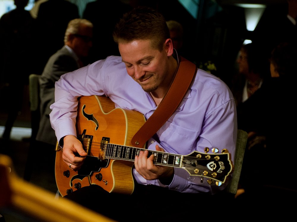 Alexander Stakenburg speelt archtopgitaar tijdens een optreden