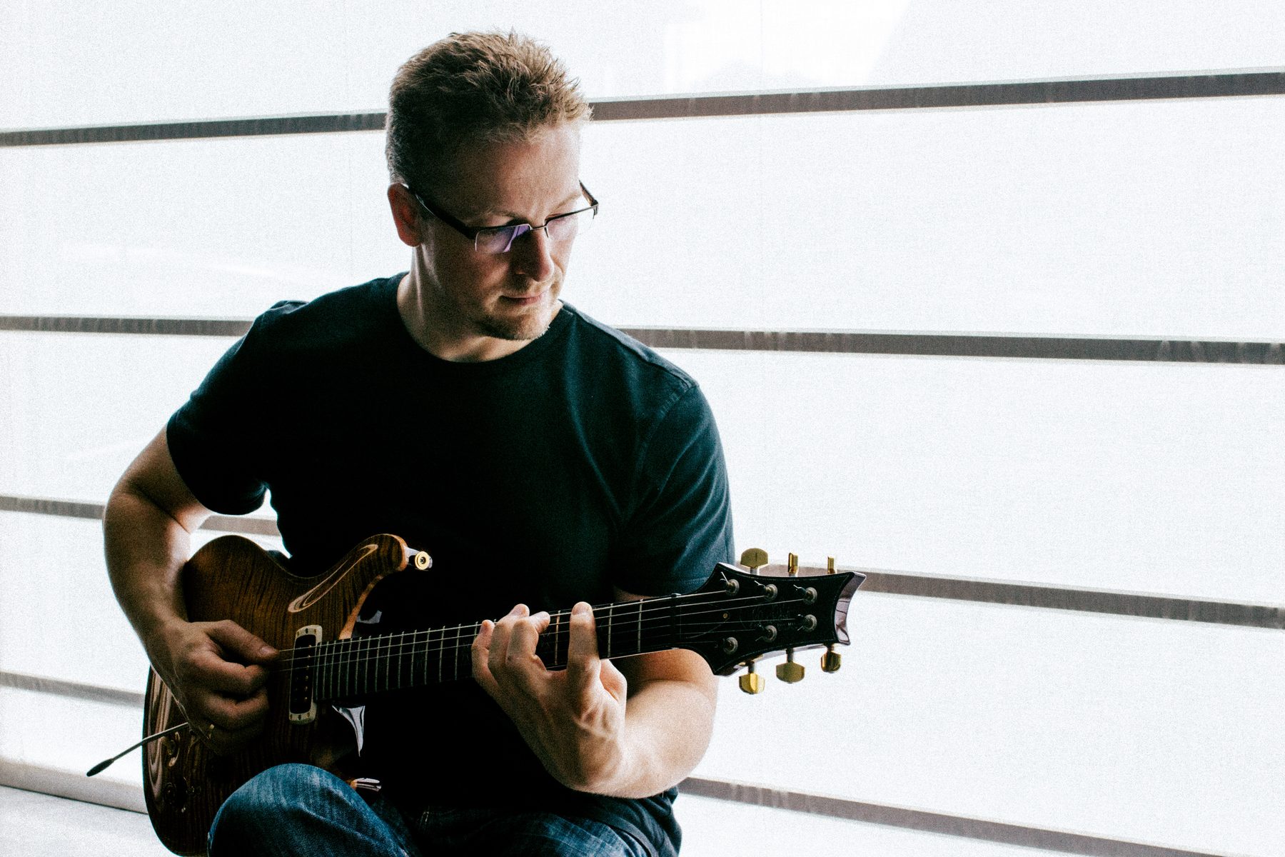 Alexander Stakenburg playing electric guitar by the window